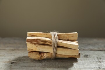 Bunch of palo santo sticks on wooden table against grey background, closeup