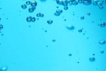 Many water bubbles on light blue background, closeup