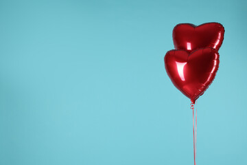 Two red heart-shaped balloons on light blue background, space for text. Happy Valentine's Day
