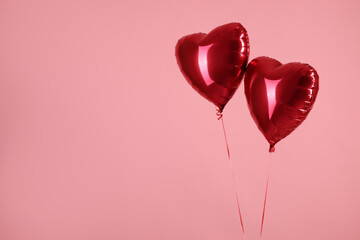 Two red heart-shaped balloons on pink background, space for text. Happy Valentine's Day