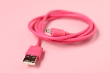 One USB charge cable on pale pink background, closeup