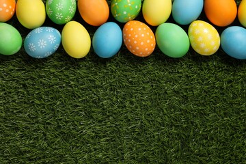 Beautiful decorated Easter eggs on green grass, flat lay. Space for text