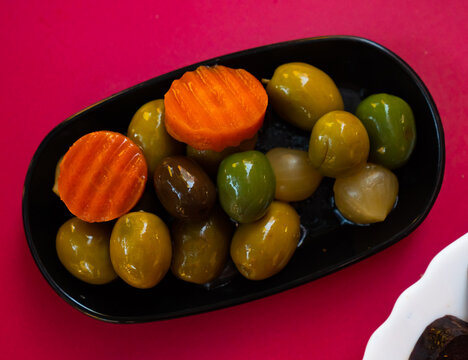 Green olives with carrot and onion on plate - typical Spanish tapas