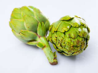 Closeup of ripe green artichoke globes on white background, selective focus. Popular vegetarian product..