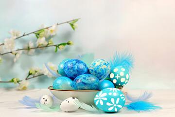 Happy Easter concept. Abstract Easter composition with blue decorated eggs, feathers, flowering branches and flowers. Banner for screen with space for greeting text