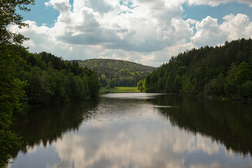 Clear Sky with Clouds Above a River Surrounded by Forests and Distant Mountains