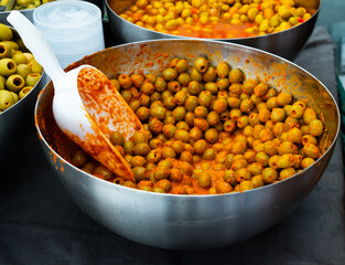 Many large green olives without pits lie in bucket in vegetable store..