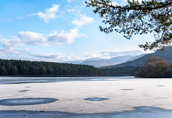Landscape photography of frozen lake Loch an Eilein, Aviemore, Scotland; UK, winter weather, snow, forest, mountains