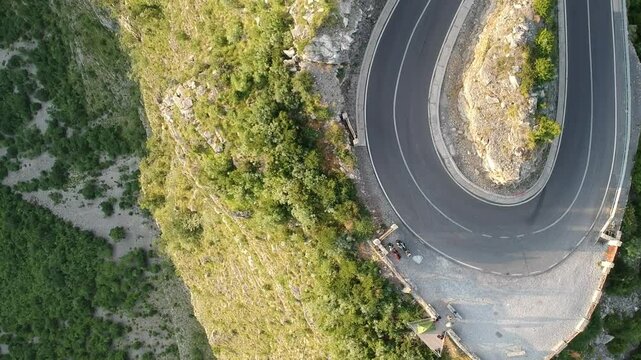Vertical Drone view of epic roads in the north albanian mountains, famous curves and hairpin turns of SH20 road above the Cem river gorge in morning. Sun is just rising over the mountains.