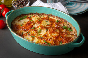 Potato gratin - graten (baked potatoes with cream and cheese) with rosemary and forks (Turkish name; Kremali patates)