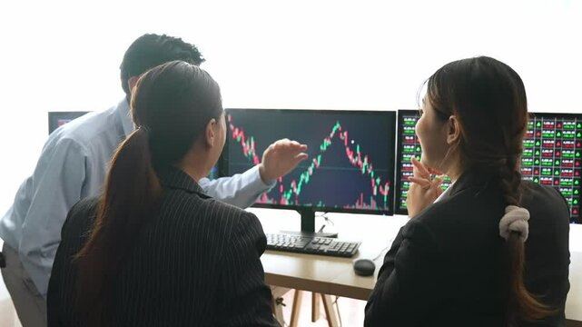 Slow motion group of business investors in stock trading company feels excited and celebrate after make profit in stock exchange marketing displayed on monitors. Burgeoning