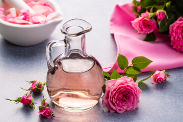 Bottles of essential rose oil and flowers