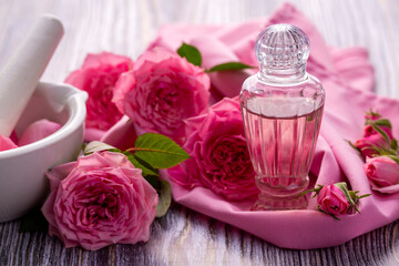 Bottles of essential rose oil and flowers