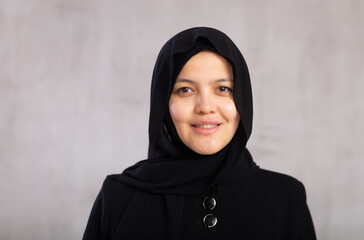 Portrait of young positive woman in hijab posing on studio background