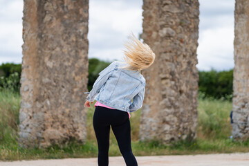 Energy of motion: a blonde woman shakes her head, and her hair dances in the wind by a viaduct in...