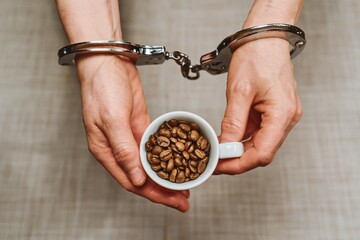 Handcuffed Hands Holding Coffee Cup with Beans