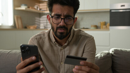Stressed Arabian Indian man frustrated upset male cardholder pay online service with bank credit...