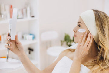 Beautician applying anti aging cream on a client's face in a professional beauty salon, enhancing skin health and promoting relaxation