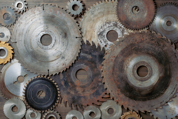 Old circular saw blades and emery wheels on wooden table, closeup, top view. Carpentry tools, sawing and grinding equipment