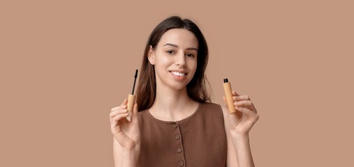 Beautiful young woman with mascara on brown background