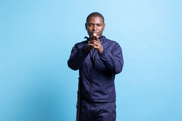 African american security agent mimicking target shooting with an imaginary gun, holding his hands...