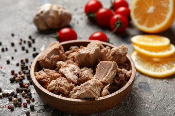 Composition with delicious canned tuna in bowl on grey grunge table
