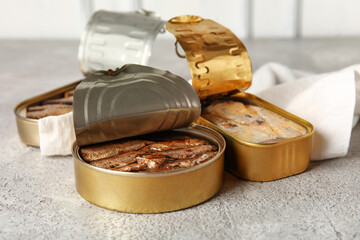 Opened tin cans with different fish on grey table