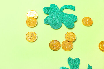 Golden coins with paper clovers on light green background. St. Patrick's Day celebration