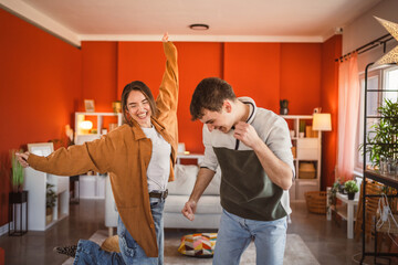 cheerful young couple have fun at home while dance energetically