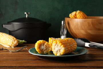 Plate with boiled corn cobs on wooden table