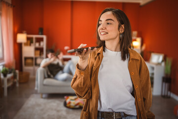 young beautiful woman record voice mail on mobile phone at home