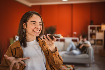 young beautiful woman record voice mail on mobile phone at home