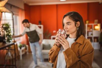 Portrait of cute young woman stand and hold glass of water at home