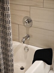 Modern bathroom design showcases a sleek tub with stylish fixtures and a textured shower curtain in...