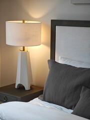Elegant bedside decor featuring a modern lamp and textured pillows in a stylish bedroom setting at dusk