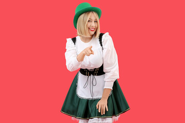 Happy woman in costume for St. Patrick's Day celebration pointing at viewer on red background