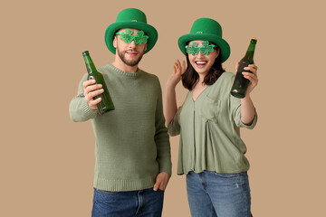 Beautiful young couple in leprechaun hats and decorative glasses in shape of clover with bottles of...