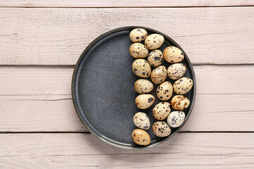 Plate with quail eggs on grey wooden background