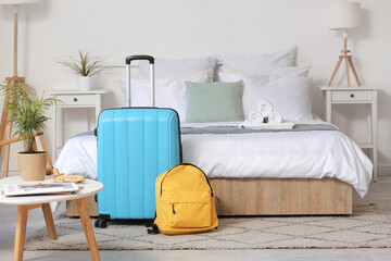 Interior of light hotel room with suitcase and backpack near bed