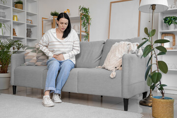 Young woman suffering from severe abdominal pain at home