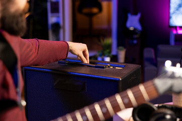 Sound engineer adjusting volume levels on his amplifier to record acoustic guitar tunes for editing...