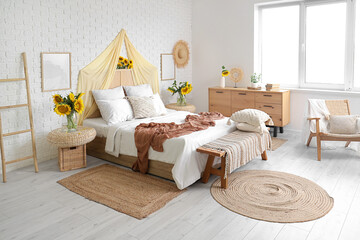 Interior of light bedroom with cozy bed and beautiful sunflowers
