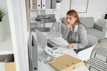 Tired businesswoman working with documents at table in office