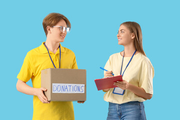 Young volunteers with donations on blue background