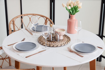 Table setting with tulips near folding screen in room