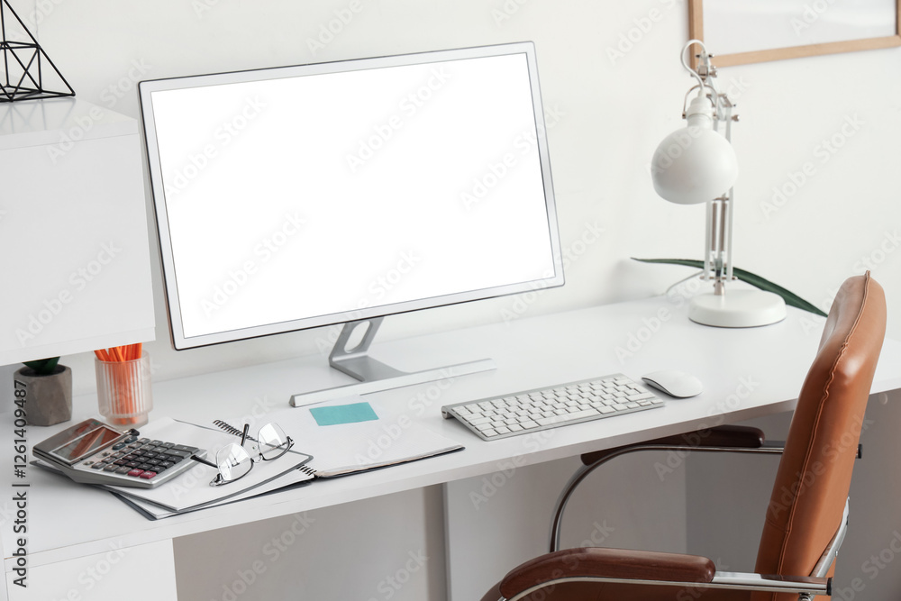 Poster workplace with blank computer monitor and lamp in light office