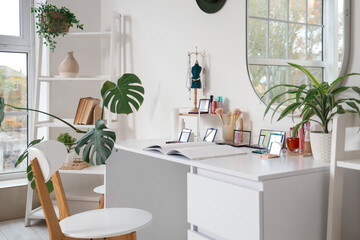 Interior of light dressing room with makeup table, mirror and shelf unit