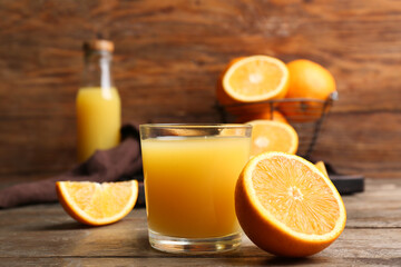 Half of fresh orange with glass of tasty juice on wooden background