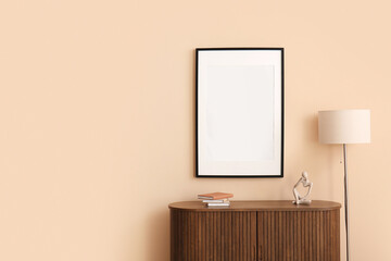 Chest of drawers with floor lamp and empty poster on beige wall