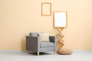Armchair with pouf, shelves and photo frames on beige wall